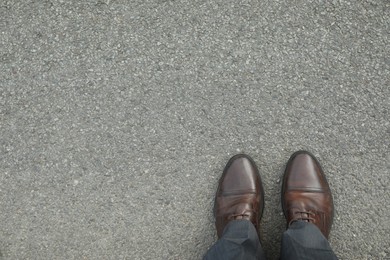 Photo of Man in brown shoes standing on asphalt, top view. Space for text