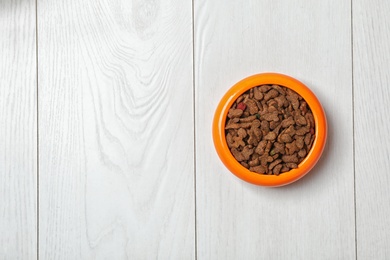 Bowl with food for cat or dog on wooden background. Pet care