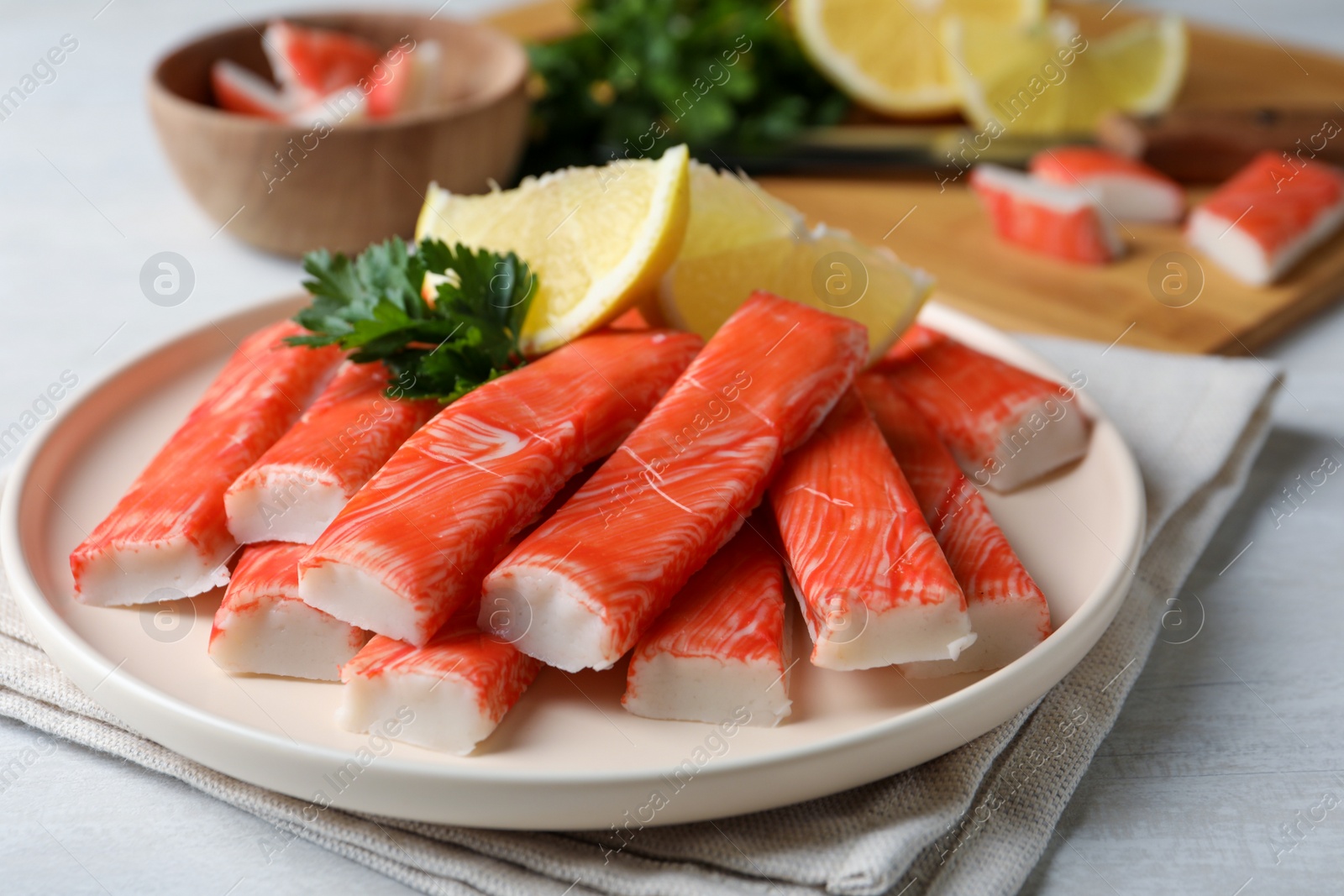 Photo of Plate of fresh crab sticks with lemon on white table, closeup