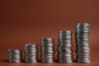 Many silver coins stacked on brown background, space for text
