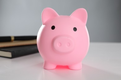 Photo of Pink piggy bank and books on white table