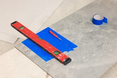 Red construction level on ceramic tile indoors