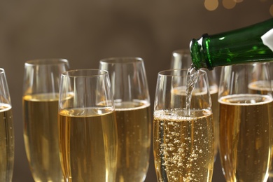 Photo of Pouring champagne into glasses on blurred background, closeup