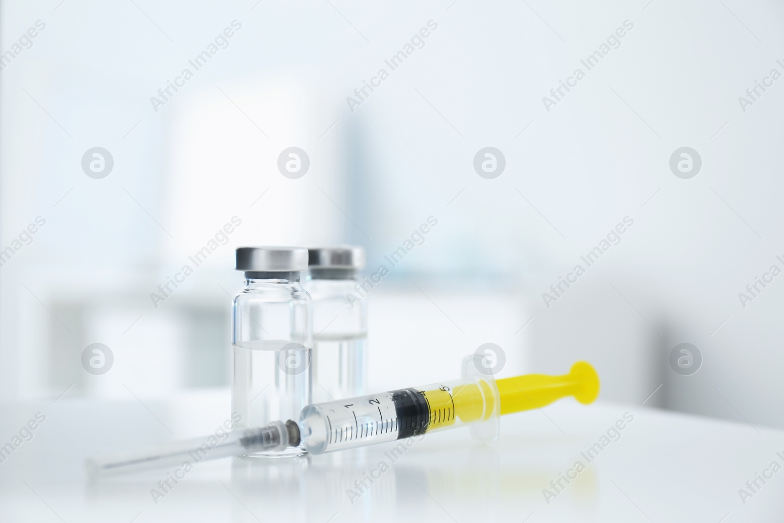 Photo of Syringe with vials of medicine on white table