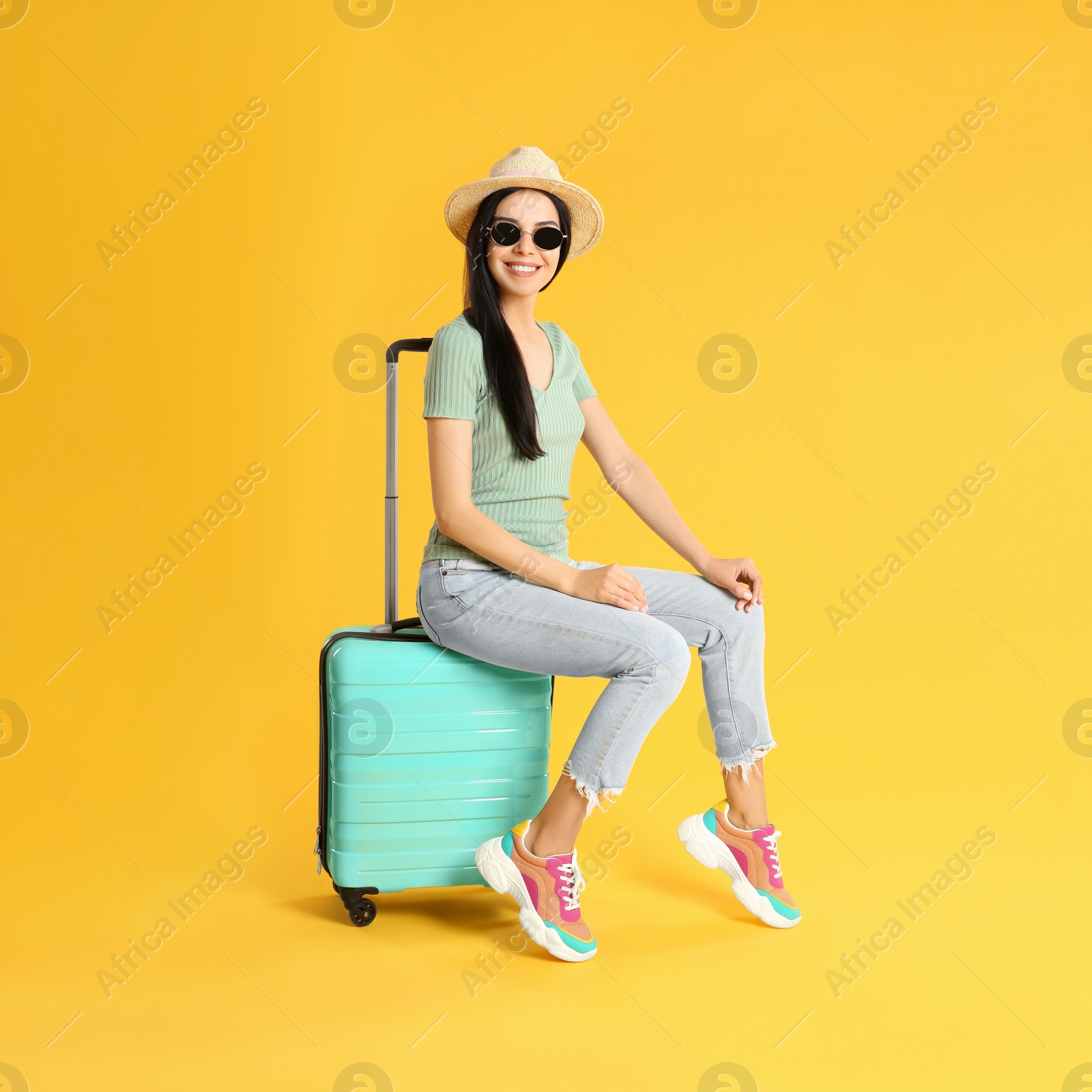 Photo of Beautiful woman with suitcase for summer trip on yellow background. Vacation travel