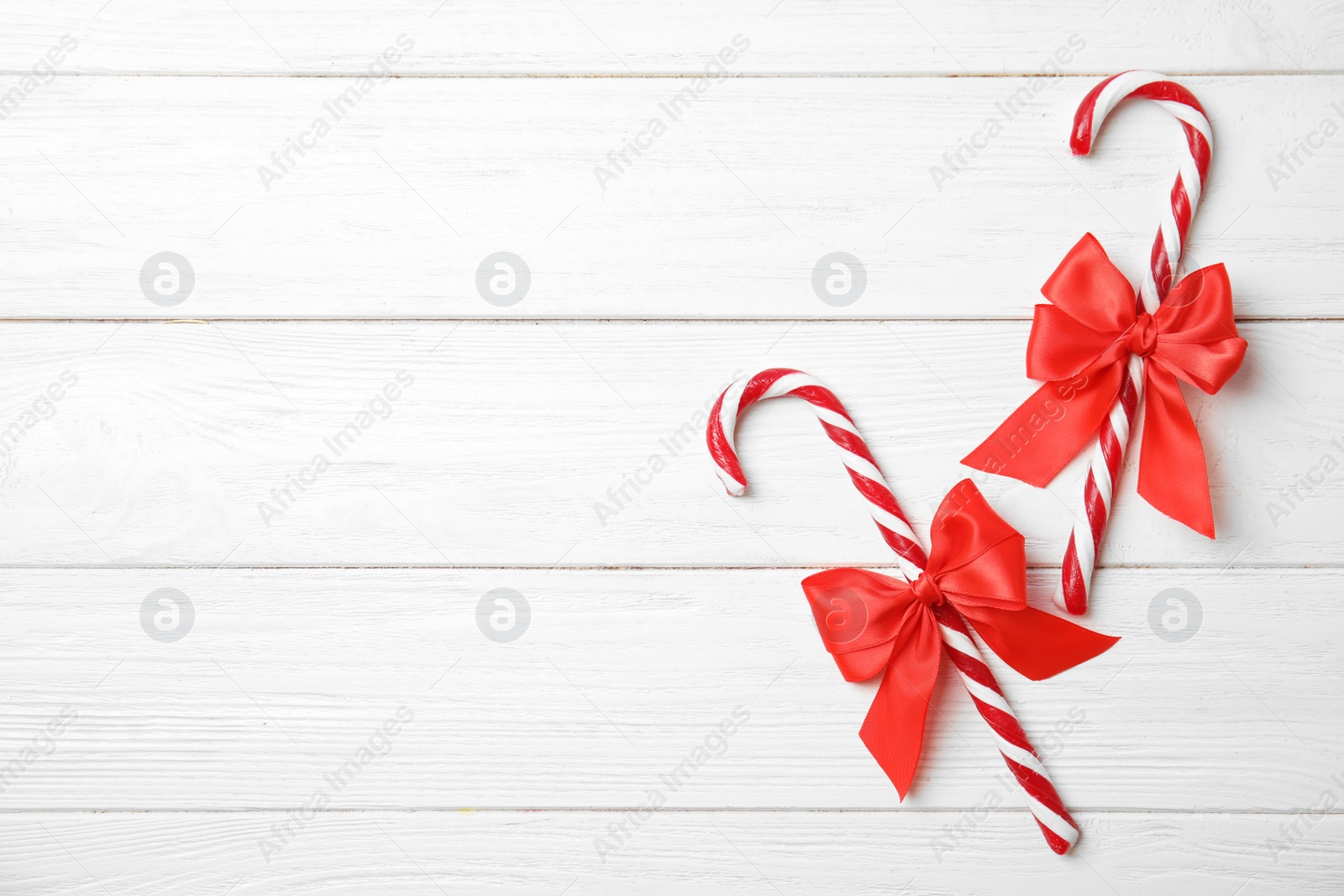 Photo of Flat lay composition with tasty candy canes and space for text on wooden background