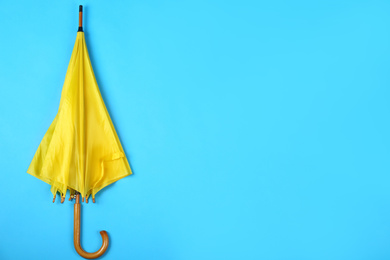 Photo of Beautiful yellow umbrella on blue background, top view. Space for text