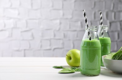Photo of Tasty fresh green smoothie near ingredients on white wooden table, space for text