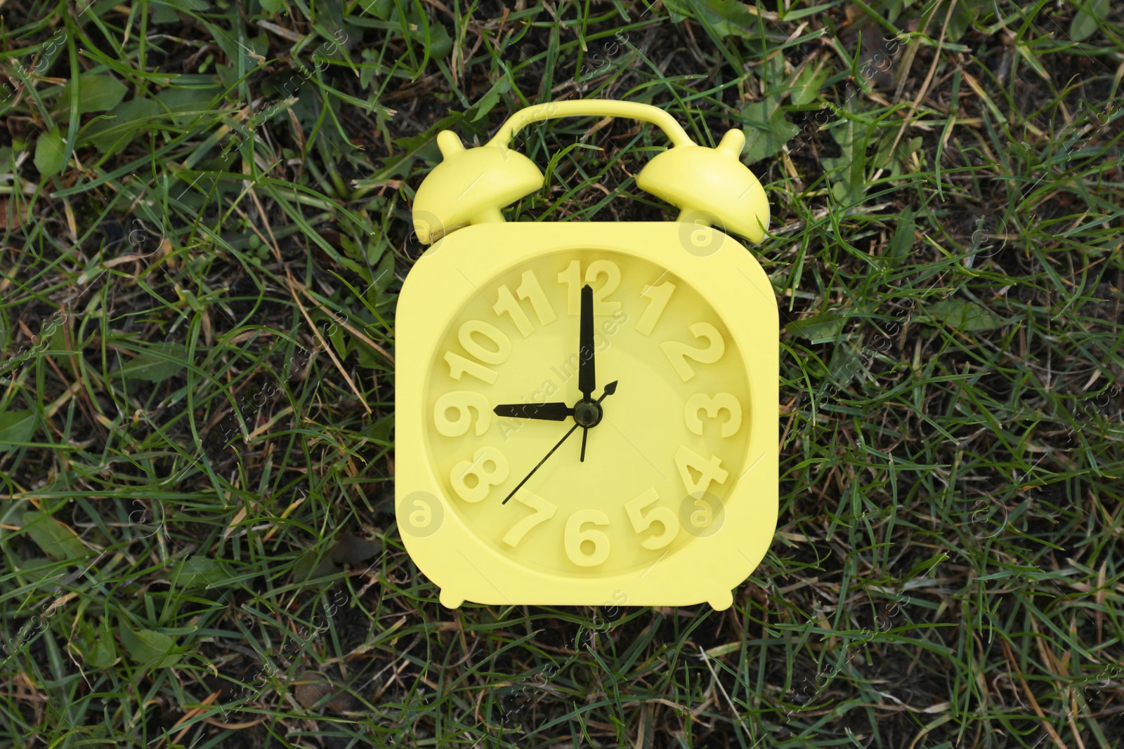 Photo of Alarm clock on green grass outdoors, top view