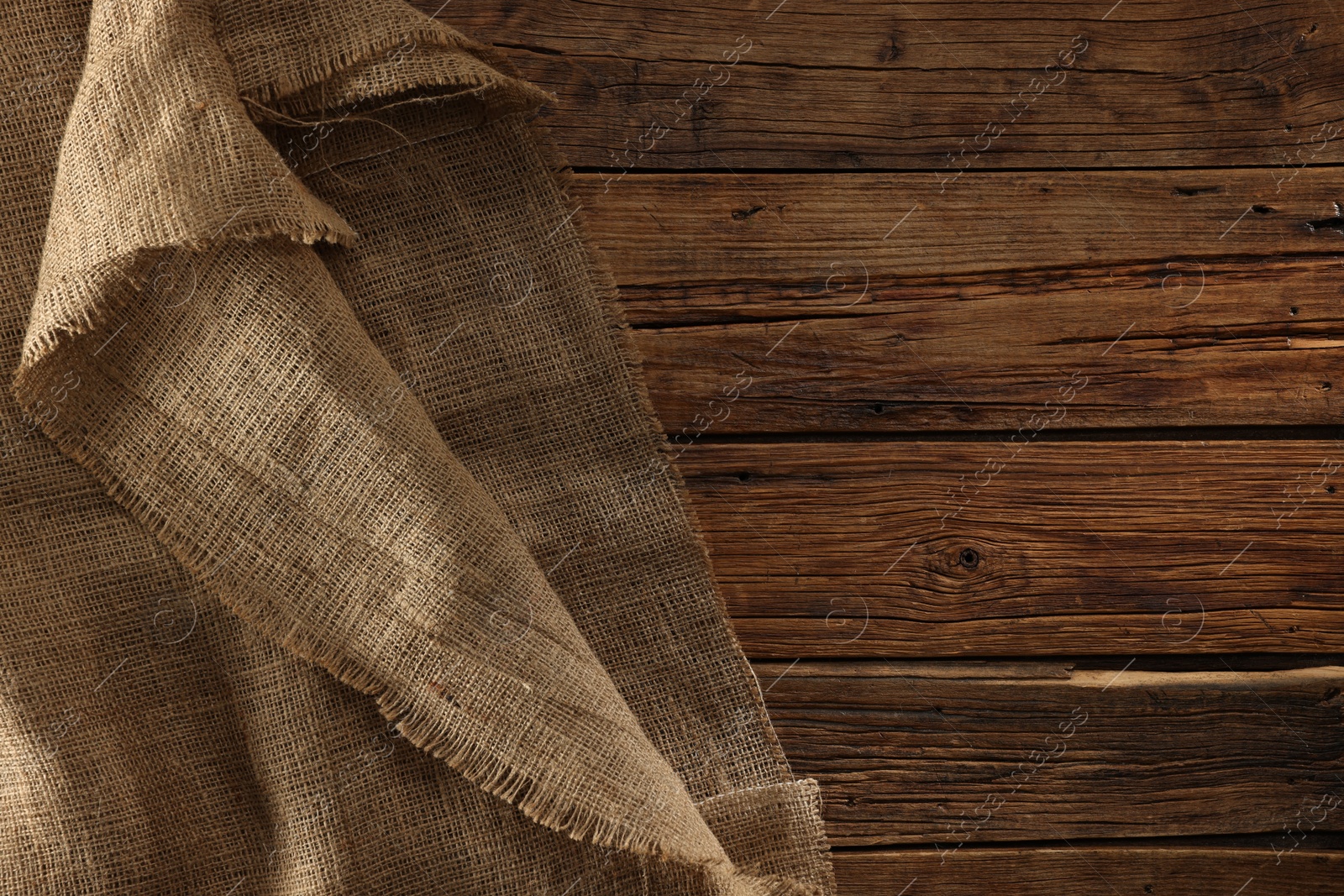 Photo of Burlap fabric on wooden table, top view. Space for text