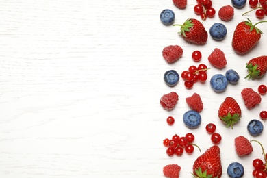 Photo of Mix of fresh berries on white wooden table, flat lay. Space for text