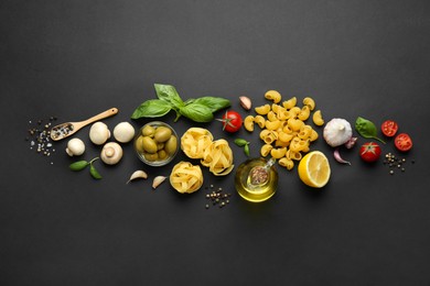 Photo of Different types of pasta, spices and products on black background, flat lay