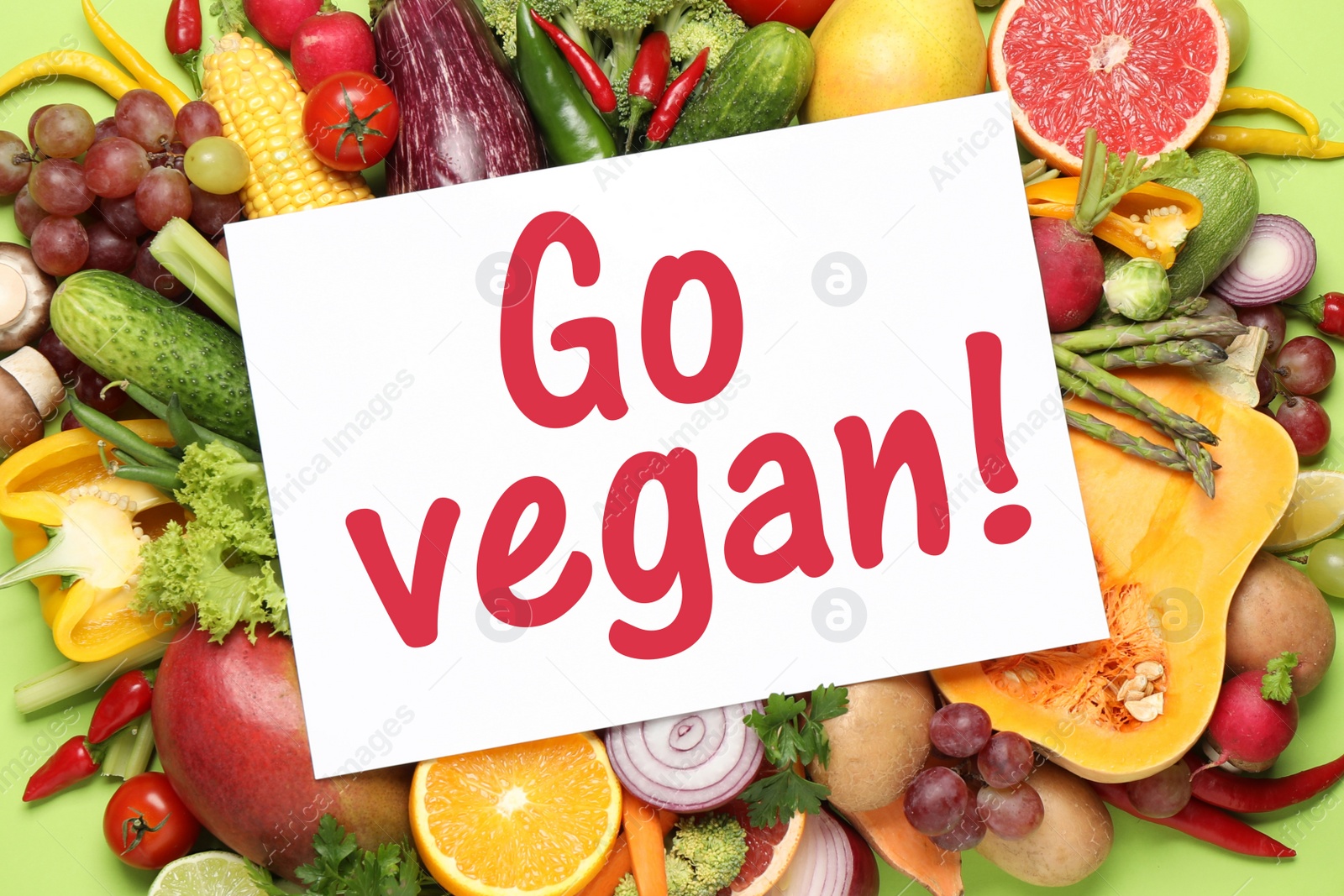 Image of Paper card with phrase Go Vegan, fresh vegetables and fruits on green background, top view