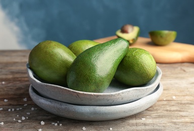 Plate with ripe avocados on wooden table