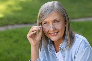 Photo of Portrait of beautiful senior woman in glasses outdoors, space for text