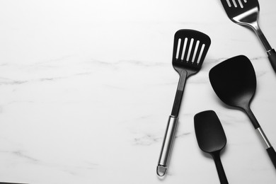 Photo of Different spatulas on white marble table, flat lay. Space for text