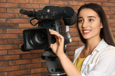 Photo of Operator with professional video camera near brick wall