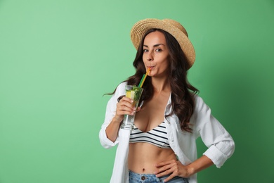 Photo of Young woman with refreshing drink on green background. Space for text