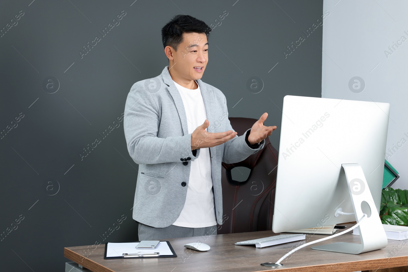Photo of Happy boss having online meeting via computer in modern office