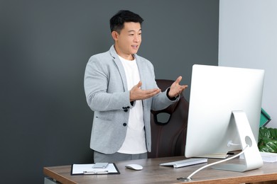 Happy boss having online meeting via computer in modern office