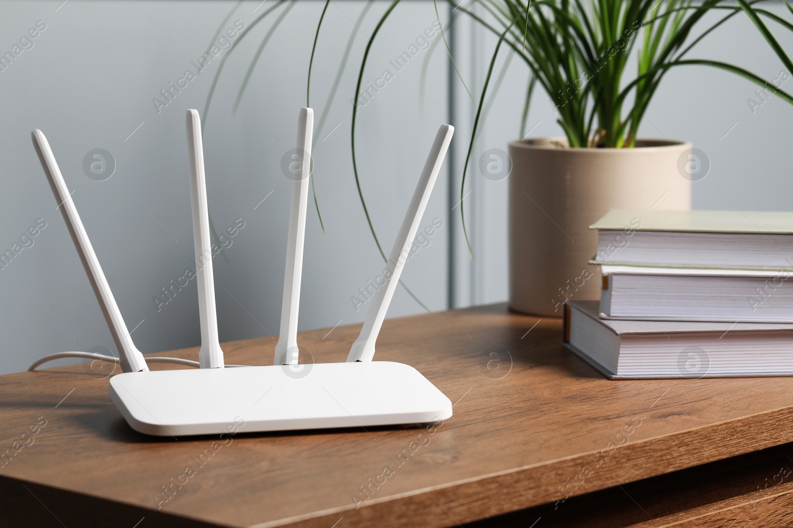 Photo of New white Wi-Fi router on wooden table indoors