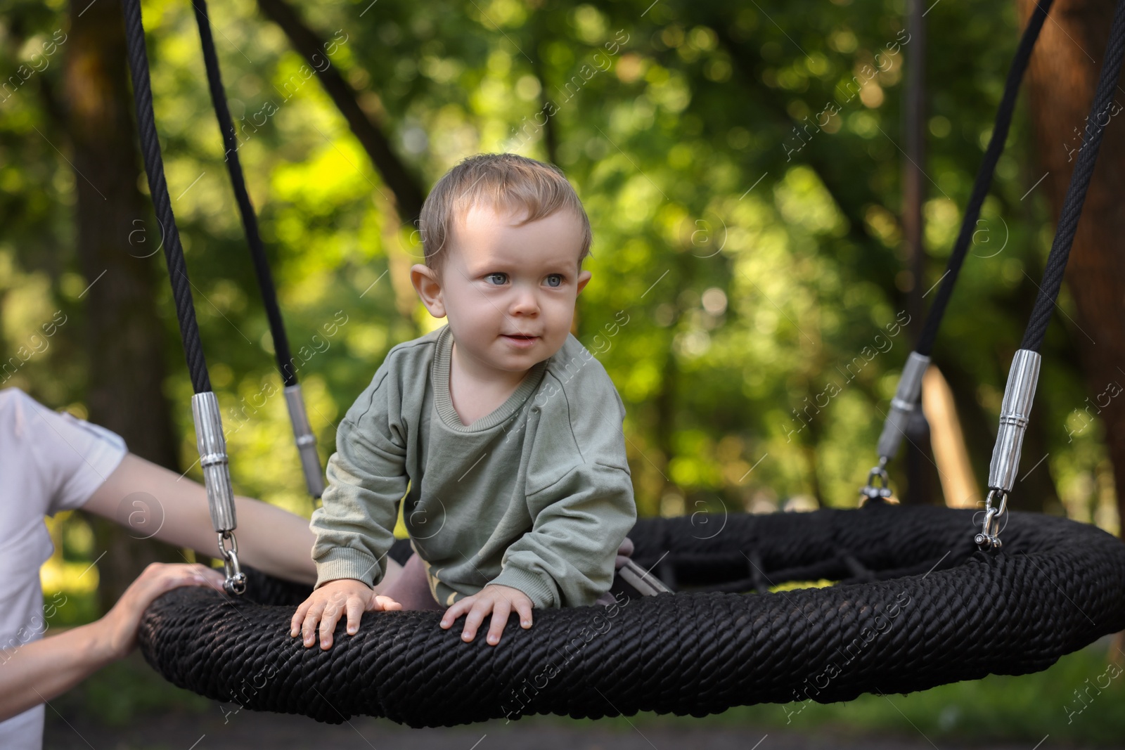 Photo of Nanny and cute little boy on swing outdoors