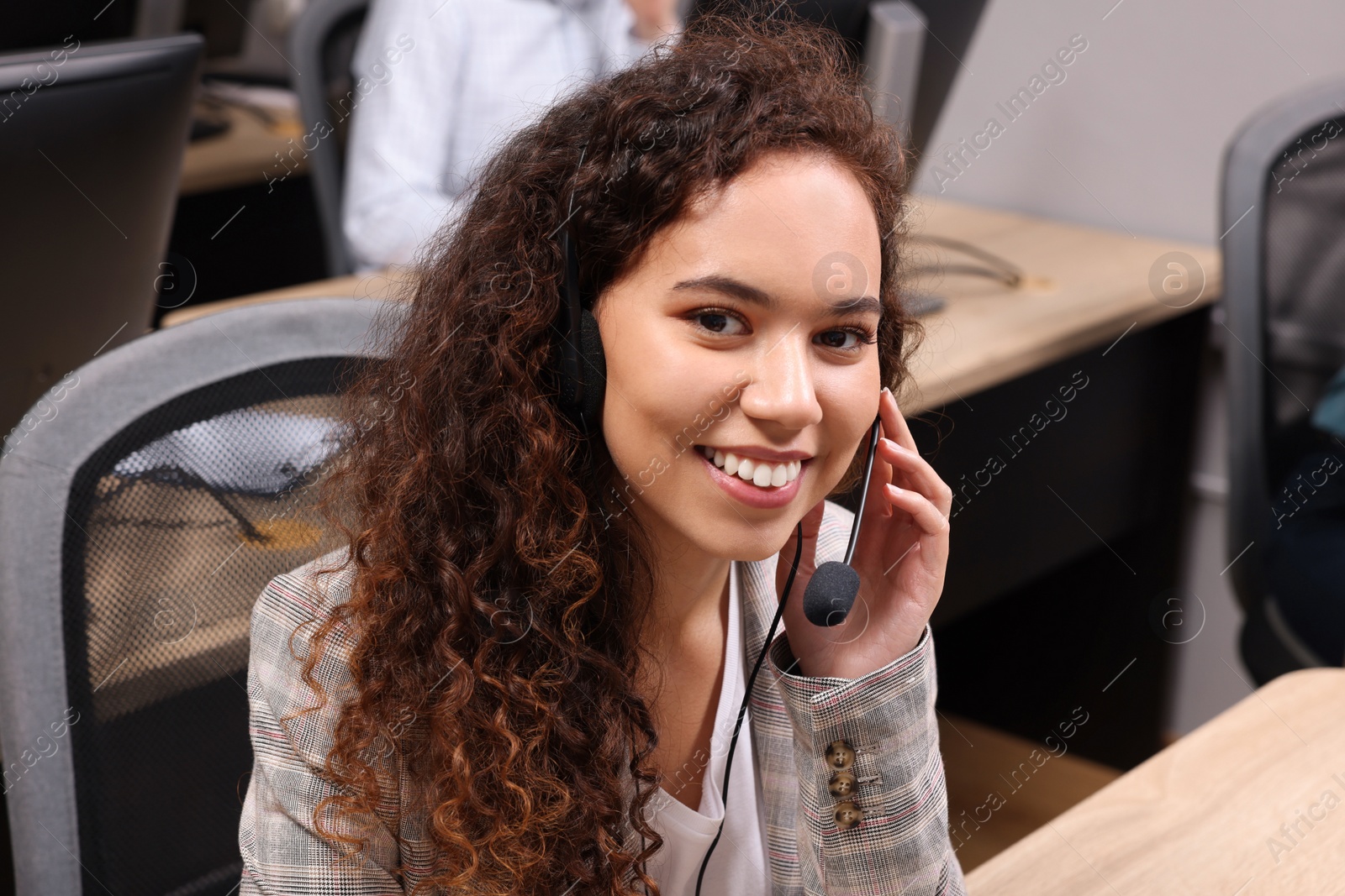 Photo of African American call center operator with headset working in modern office