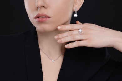 Photo of Woman with elegant jewelry on black background, closeup