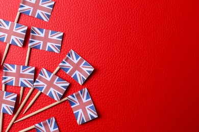 Photo of Small paper flags of United Kingdom on red textured background, flat lay. Space for text