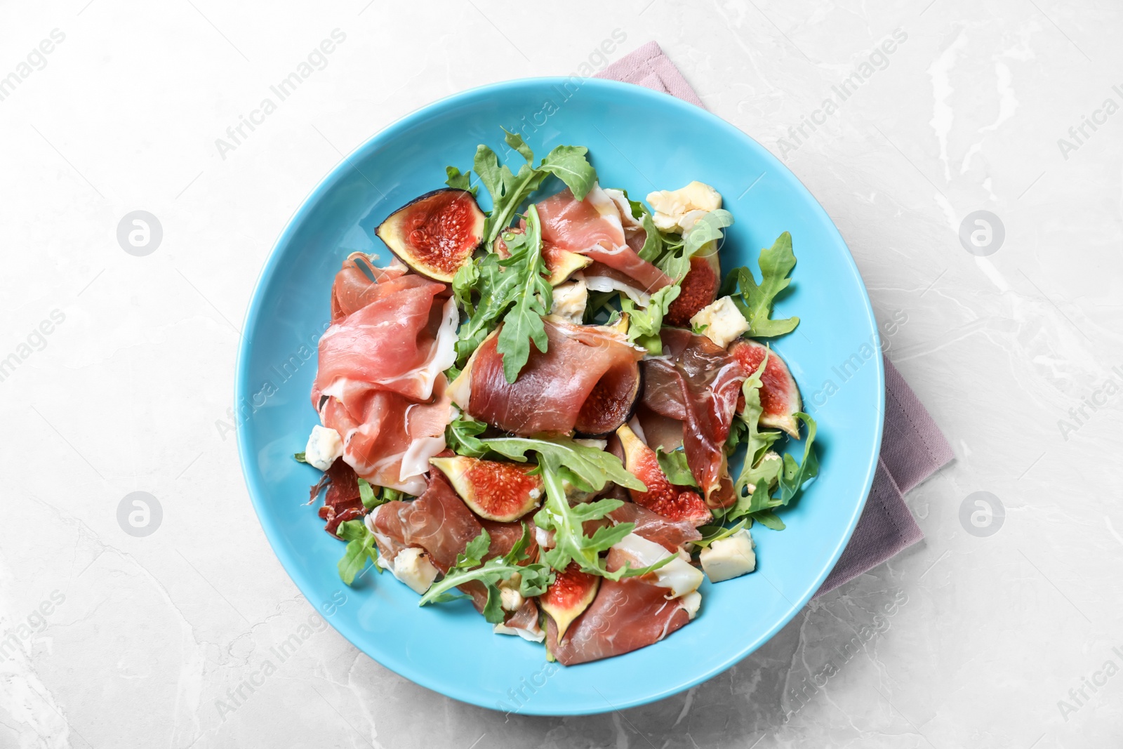Photo of Salad with ripe figs and prosciutto served on grey marble table, top view