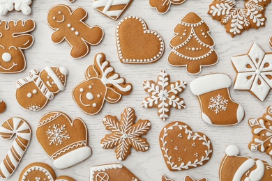 Photo of Different Christmas gingerbread cookies on white wooden table, flat lay