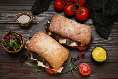 Delicious sandwiches with tasty filling and ingredients on wooden table, flat lay
