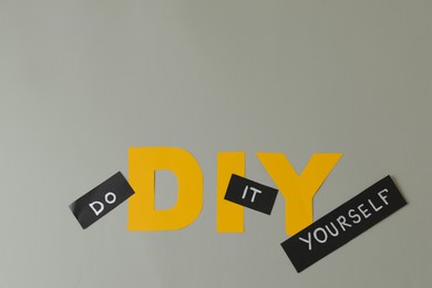 Photo of Phrase Do It Yourself and abbreviation DIY made of letters on light grey background, flat lay. Space for text
