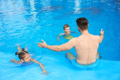 Young father with little children in swimming pool on sunny day