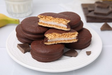 Photo of Tasty banana choco pies and pieces of chocolate on white table, closeup