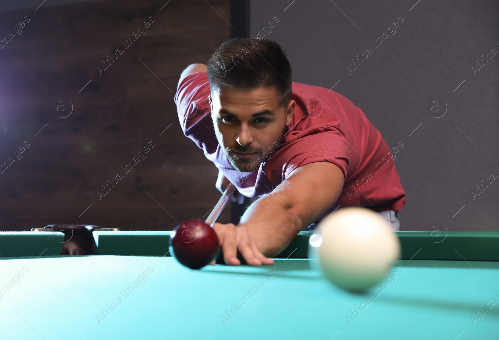 Photo of Handsome young man playing Russian billiard indoors