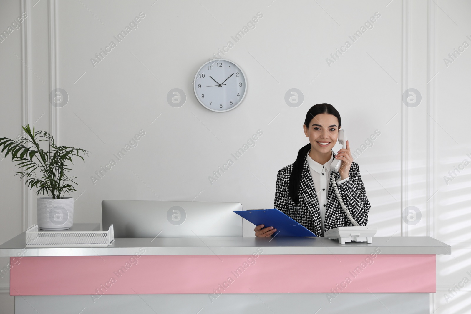 Photo of Receptionist talking on phone at countertop in office