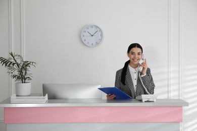 Receptionist talking on phone at countertop in office