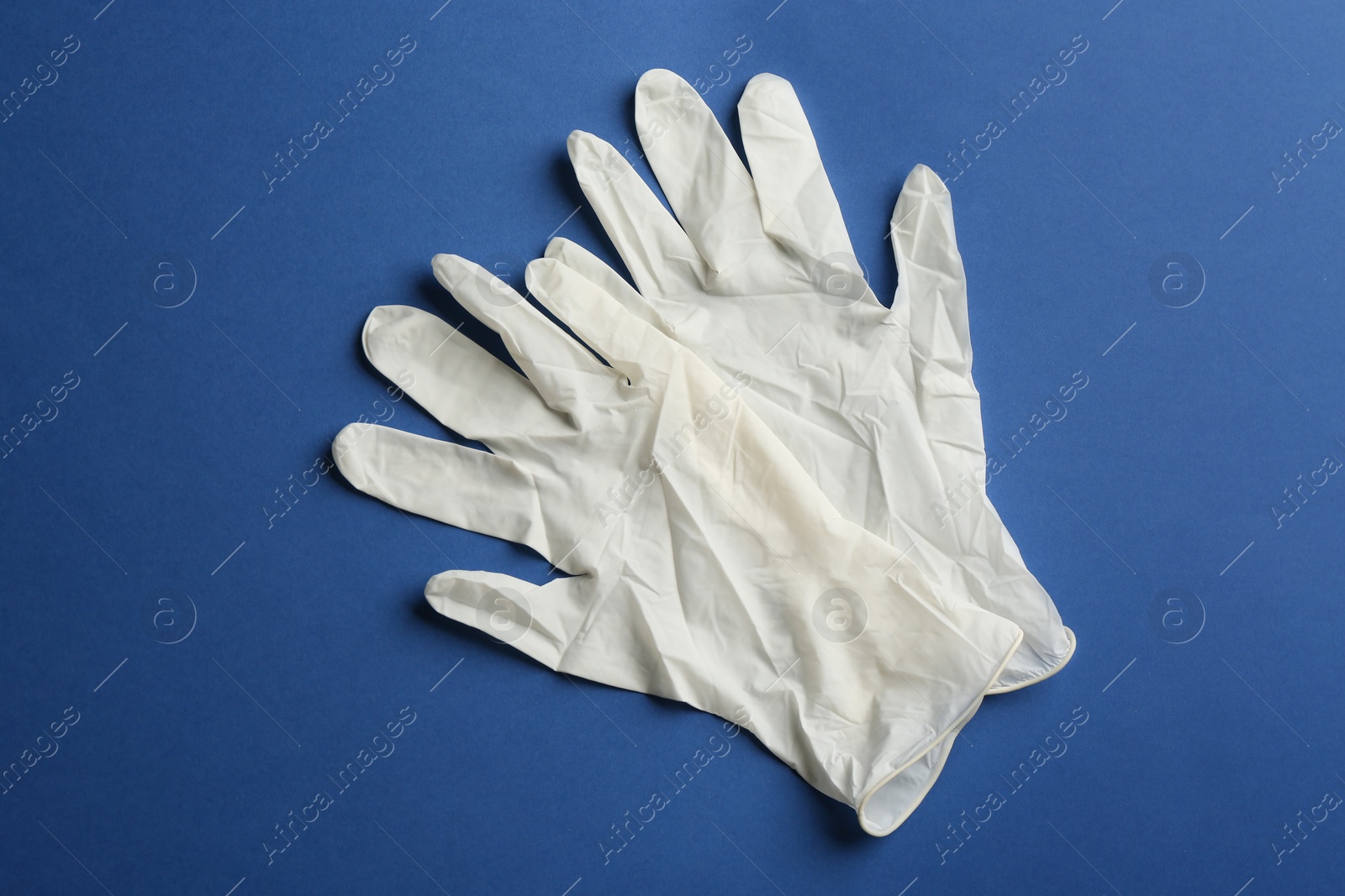 Photo of Pair of medical gloves on blue background, flat lay