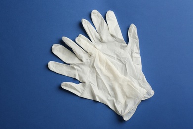 Photo of Pair of medical gloves on blue background, flat lay