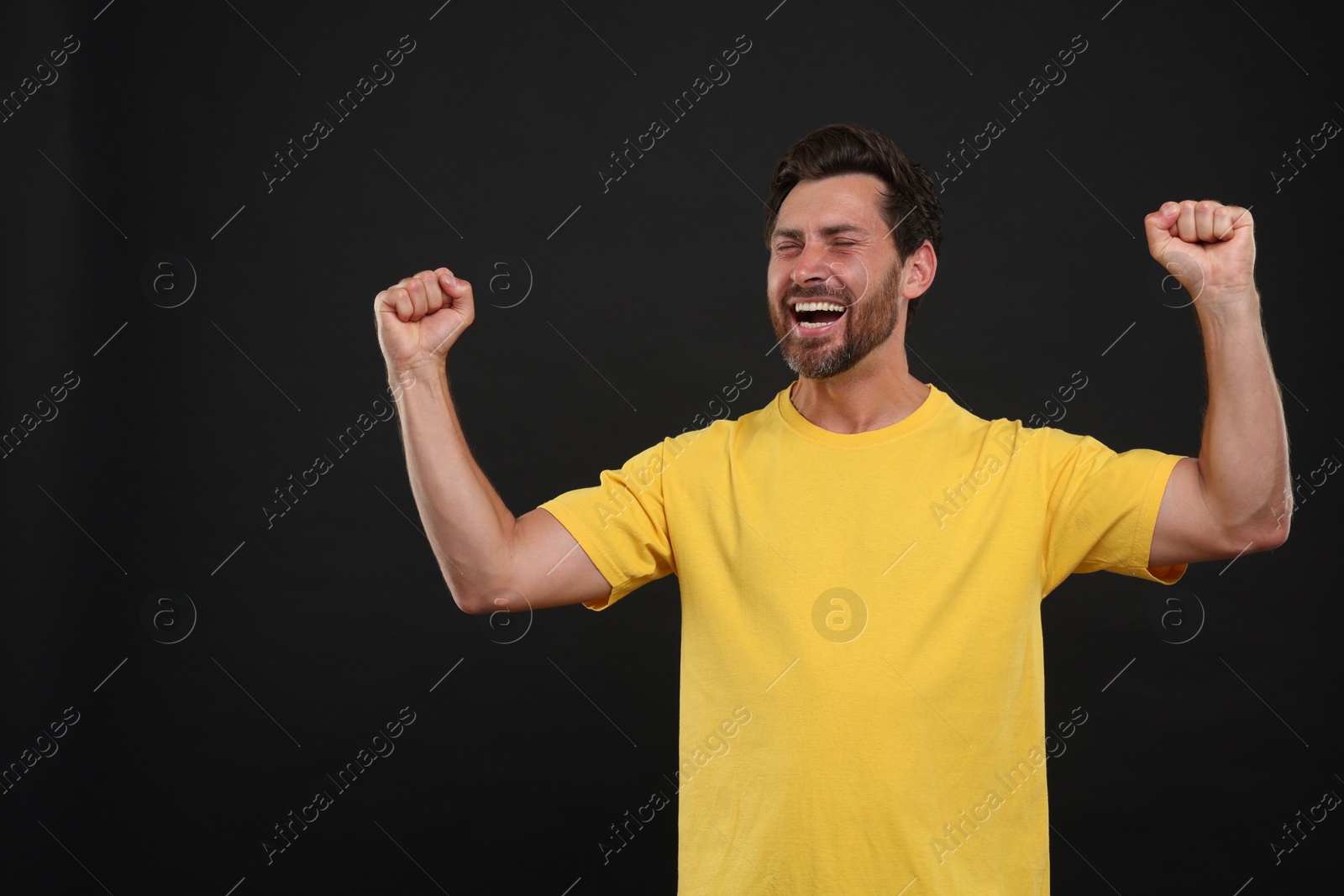 Photo of Emotional sports fan celebrating on black background