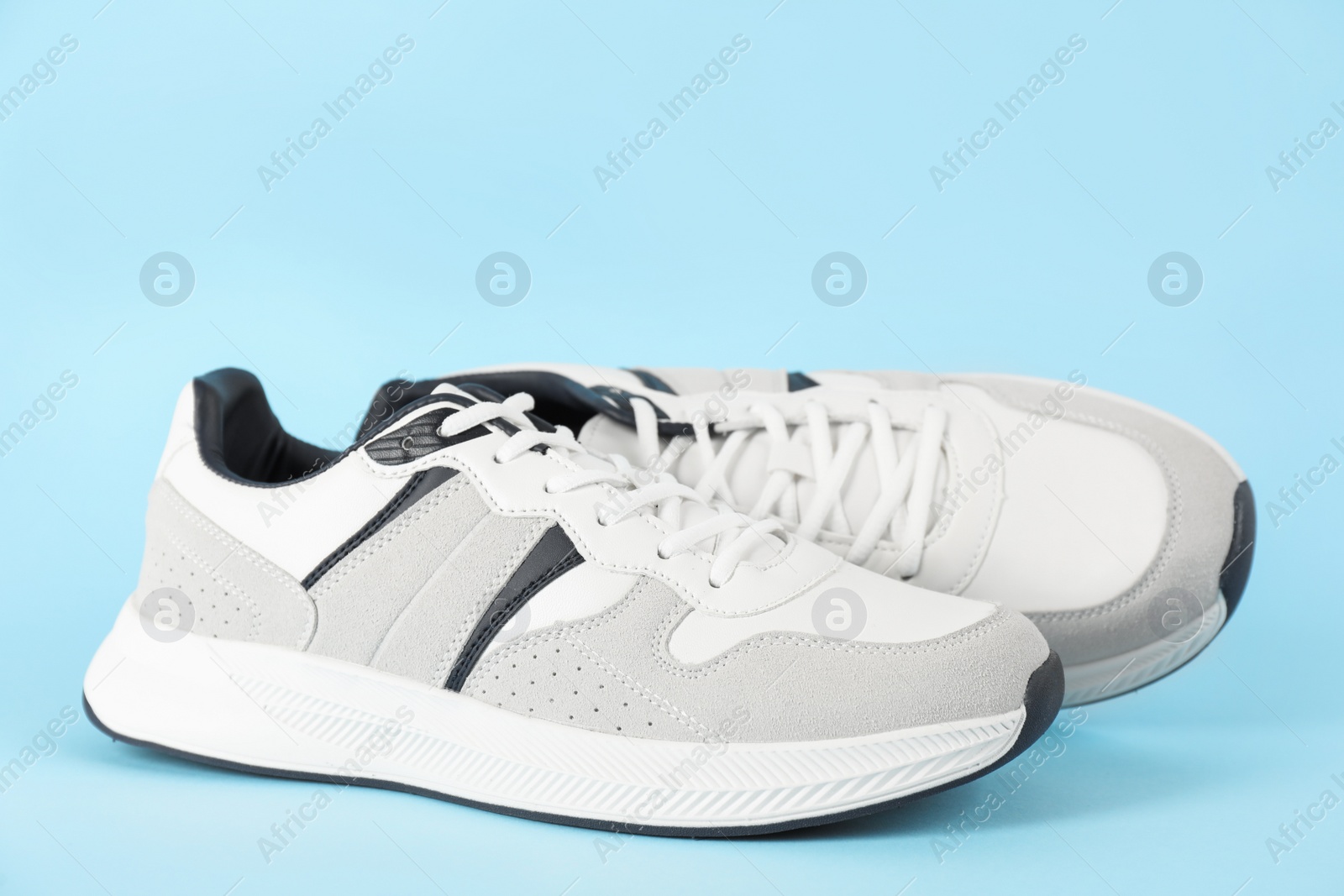 Photo of Pair of stylish sneakers on light blue background. Space for text