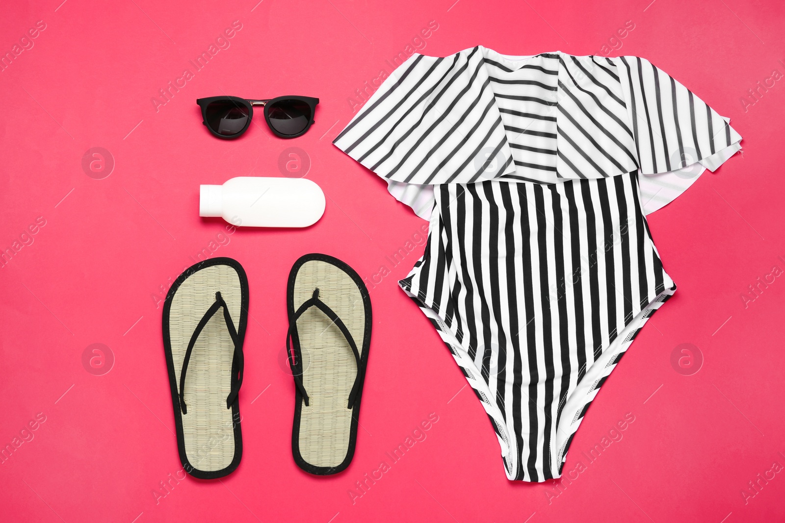 Photo of Flat lay composition with striped swimsuit and beach accessories on coral background