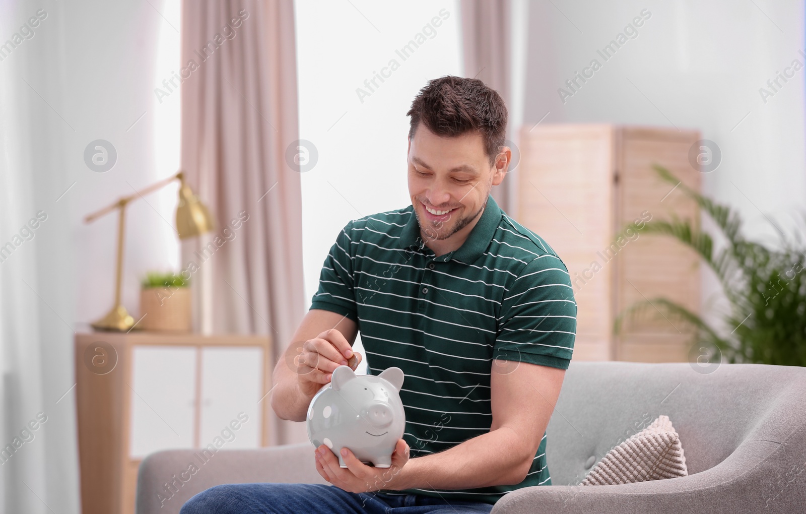 Photo of Man with piggy bank and money at home