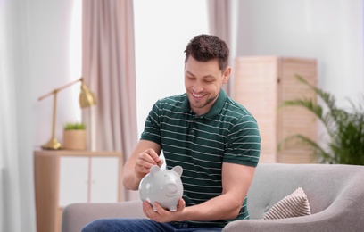 Man with piggy bank and money at home