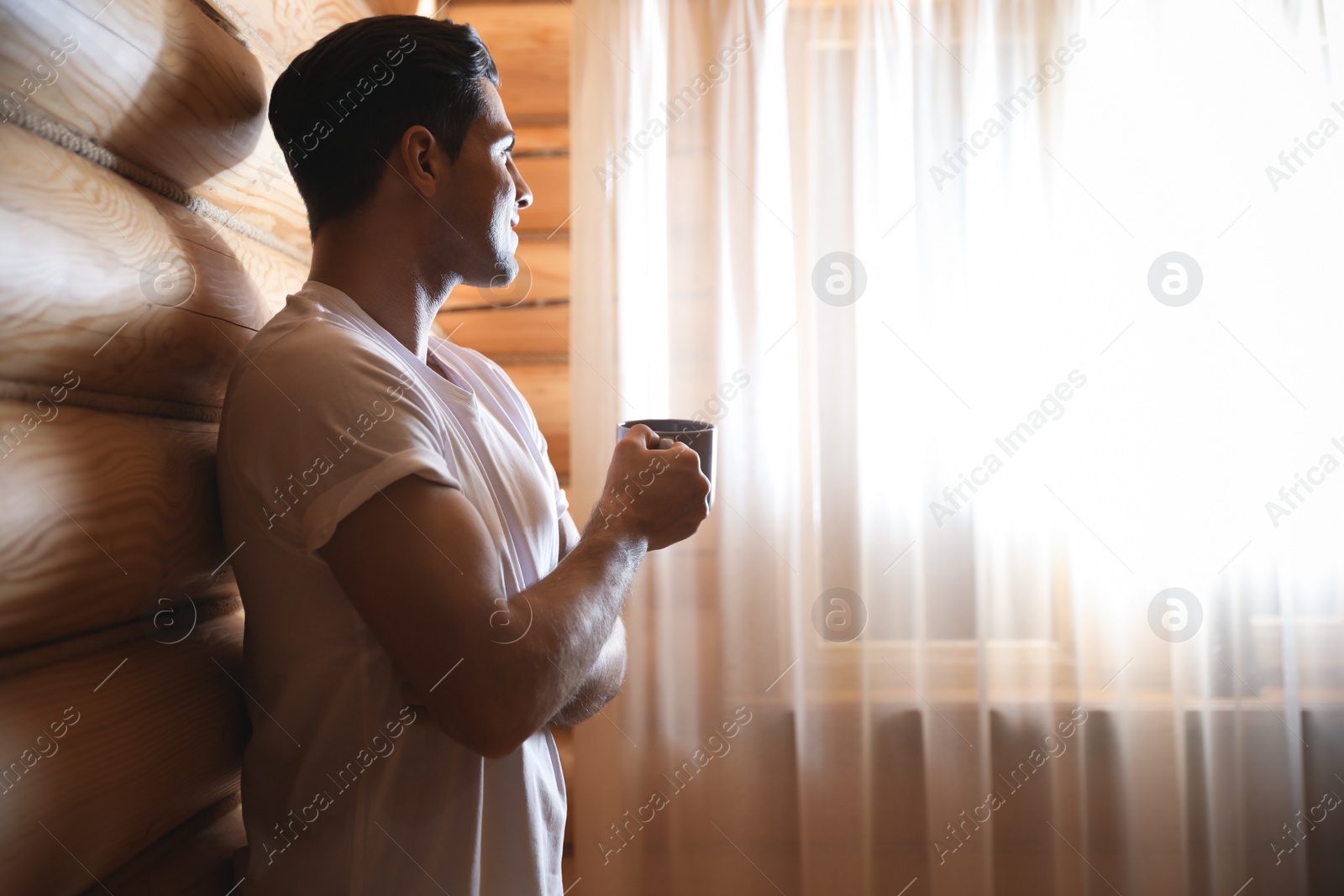 Photo of Man with drink near window indoors. Lazy morning