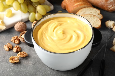 Photo of Pot with delicious cheese fondue on gray table