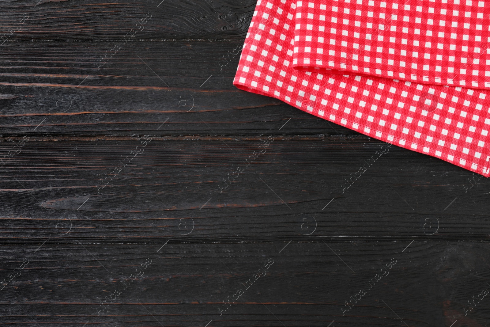 Photo of Checkered picnic blanket on color wooden background, top view. Space for text