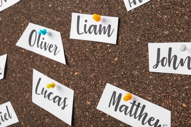 Photo of Paper pieces with baby names on cork board, closeup