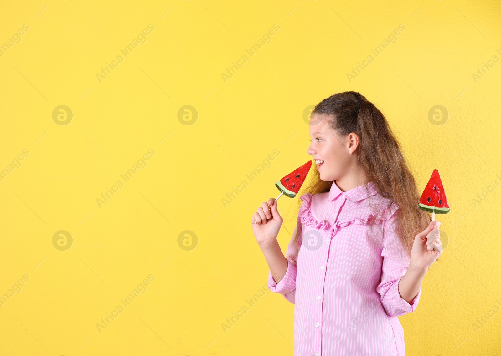 Photo of Little girl with candies on color background. Space for text
